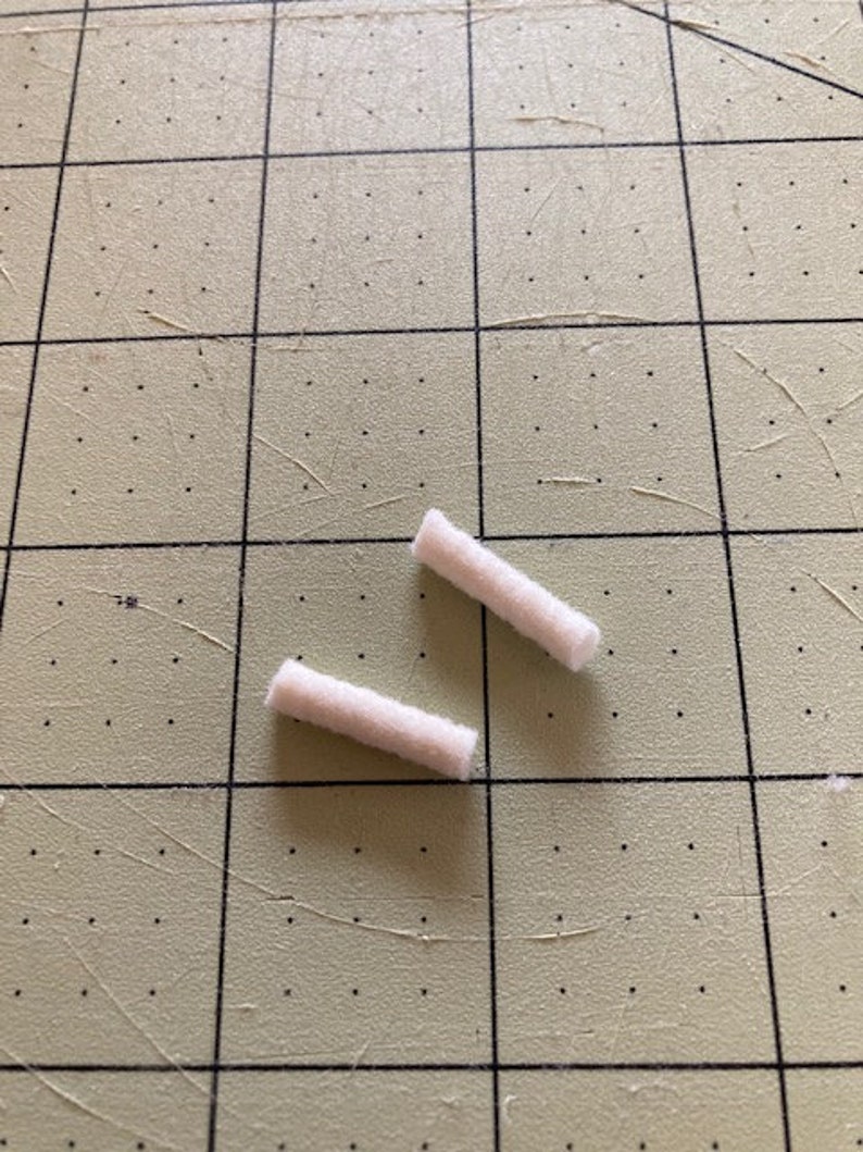 May include: Two white cotton swabs on a green cutting mat.