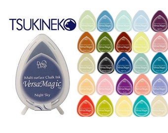 May include: A collection of 25 VersaMagic chalk ink pads in various colors, including Night Sky,  Sage,  and  Tangerine. The ink pads are shaped like teardrops and have a clear plastic casing. The ink pads are arranged in a grid pattern on a white background.