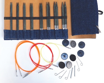 Puede incluir: Un juego de agujas circulares intercambiables en una funda de cuero marrón y denim. El juego incluye una variedad de tamaños de agujas, así como un juego de cables, marcadores de puntos y un enhebrador de agujas.