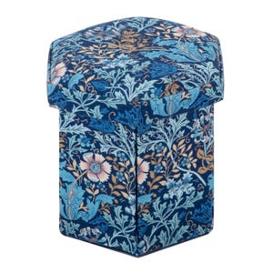 Pode incluir: Pufe de armazenamento hexagonal com um padrão floral em tons de azul, rosa e dourado. O tecido apresenta um design botânico detalhado com flores e folhas. Uma peça de mobiliário decorativa e funcional.