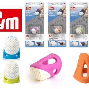Peut inclure: Assortiment de dé à coudre pour la couture, de différentes couleurs. Les dé à coudre sont en silicone et ont un motif en nid d'abeille. Les dé à coudre sont disponibles en orange, bleu, violet, vert et rose. Les dé à coudre sont conçus pour être confortables à porter et protéger le doigt pendant la couture.