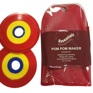 May include: Two red, yellow, and blue plastic pom pom makers in a clear plastic bag with a red backing. The bag has the text "Essentials All your knitting needs POM POM MAKER Imported for ESSENTIALS BRAND Whitecroft Lydney Gloucestershire England GL 15 4QG"