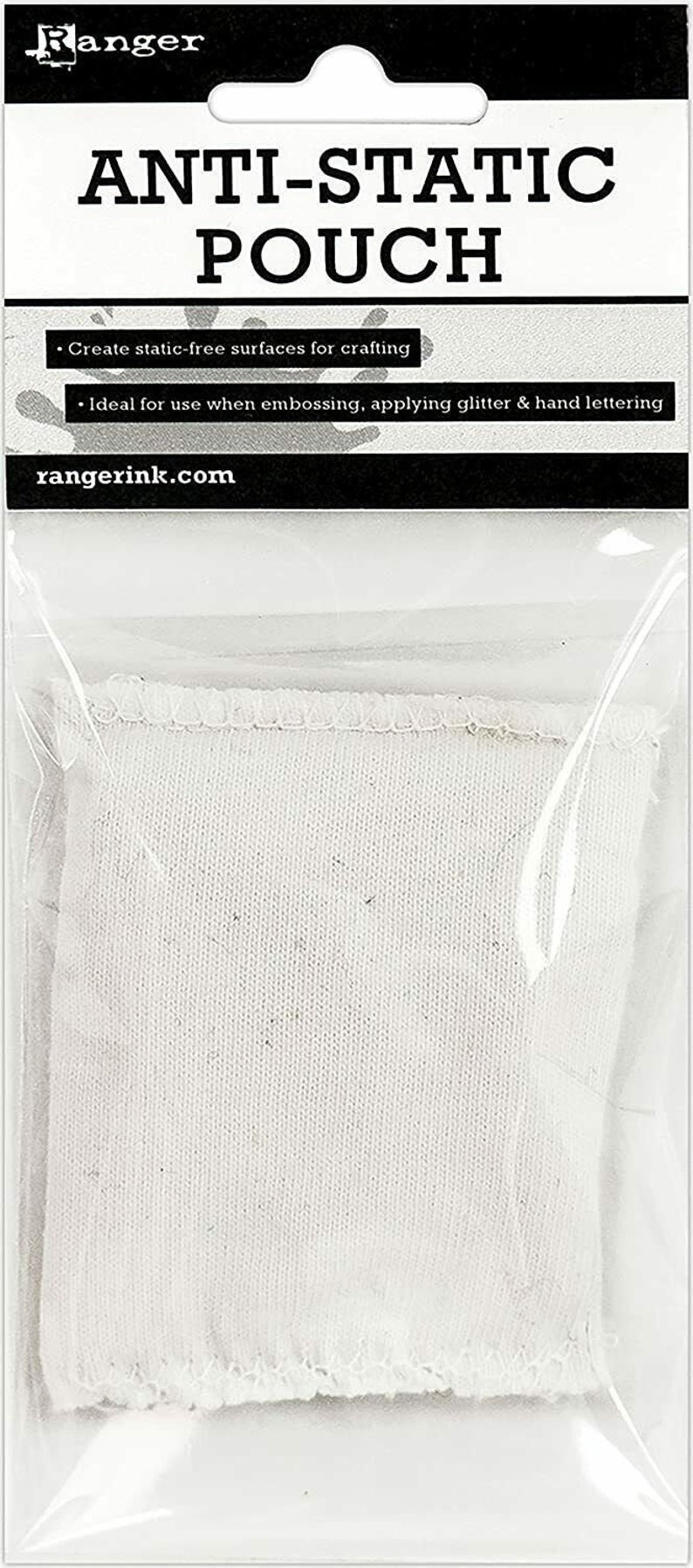 Peut inclure: Pochette antistatique en tissu blanc avec l'inscription "Anti-Static Pouch" et le texte "Create static-free surfaces for crafting. Ideal for use when embossing, applying glitter & hand lettering. rangerink.com"