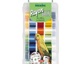 May include: A clear plastic box with a green handle contains 40 spools of Madeira Rayon thread, each 1000 meters long. The box also includes a bonus embroidery design CD and a needle pack. The spools are arranged in rows and are in various colors, including yellow, orange, green, blue, and white. The box is labeled "Rayon Box" and "Madeira".