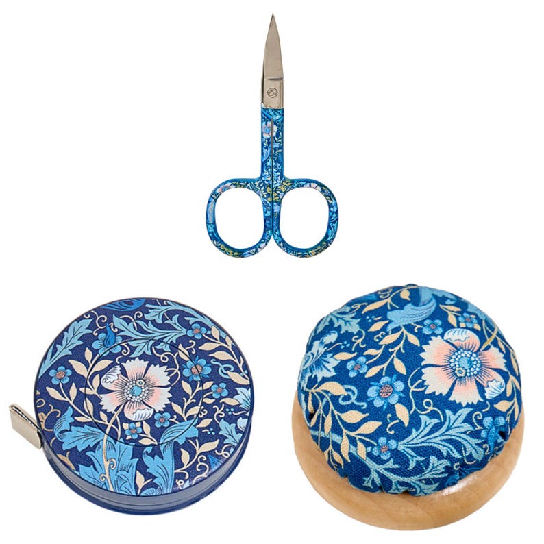 Puede incluir: Un juego de costura con una cinta m&eacute;trica, un alfiletero y unas tijeras peque&ntilde;as. Los art&iacute;culos tienen un estampado floral azul con detalles en rosa y crema. La cinta m&eacute;trica es redonda y el alfiletero est&aacute; sobre una base de madera.
