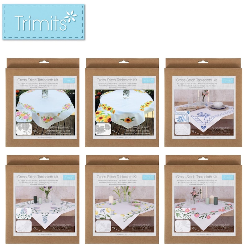 May include: A collection of six cross-stitch tablecloth kits in brown cardboard packaging. Each kit features a different floral design, including roses, sunflowers, and other flowers. The kits are labeled "Cross Stitch Tablecloth Kit" and include the brand name "Trimits".