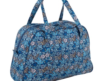 May include: A blue floral patterned duffel bag with two handles and a zipper closure. The bag features a repeating pattern of flowers and leaves in shades of blue, white, and brown. The bag is designed for travel or carrying items.