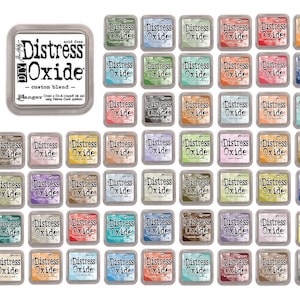 Könnte beinhalten: Eine Sammlung von 36 Distress Oxide Stempelkissen in verschiedenen Farben. Die Stempelkissen sind in einem Raster angeordnet und tragen auf der Vorderseite den Text "Distress Oxide" und "Custom Blend".