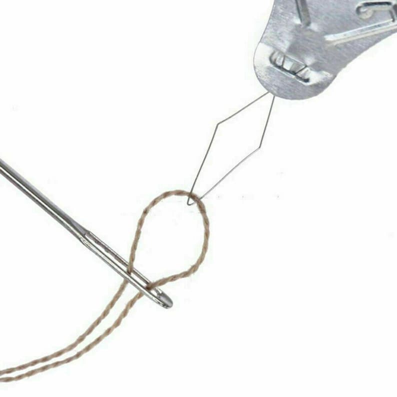 May include: A metal needle threader with a loop at the end of the needle. The needle is threaded with a brown string.