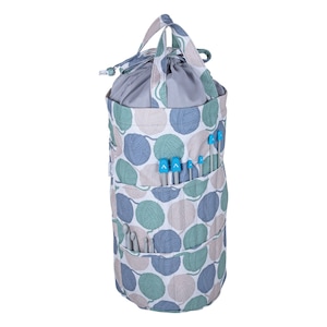 May include: A gray and white yarn bag with a drawstring top and a handle. The bag has a pattern of green and blue yarn balls. The bag has multiple pockets on the side for storing knitting needles and crochet hooks.