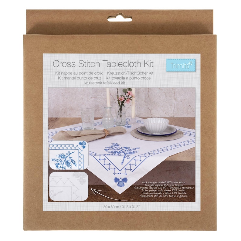 May include: A cross stitch tablecloth kit in a cardboard package. The white tablecloth features a blue floral design and geometric border. The package includes the text "Cross Stitch Tablecloth Kit" and measurements of 31.5 x 31.5 inches.