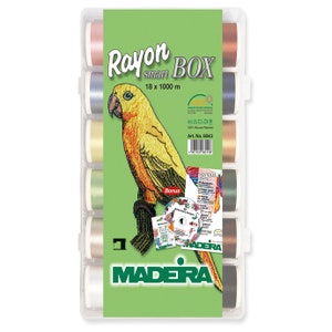 May include: A box containing 18 spools of Madeira Rayon Smart embroidery thread, each spool is 1000 metres long. The box includes a bonus CD and a colour card. The box is green and white with the Madeira logo. The spools are arranged in a row and are in various colours, including pink, blue, yellow, green, brown, and black.