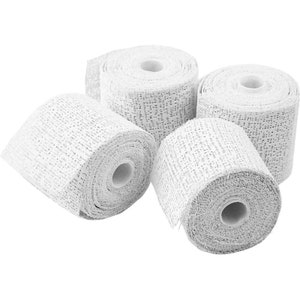 May include: Four rolls of white gauze bandage, a medical supply used for wound care and support.