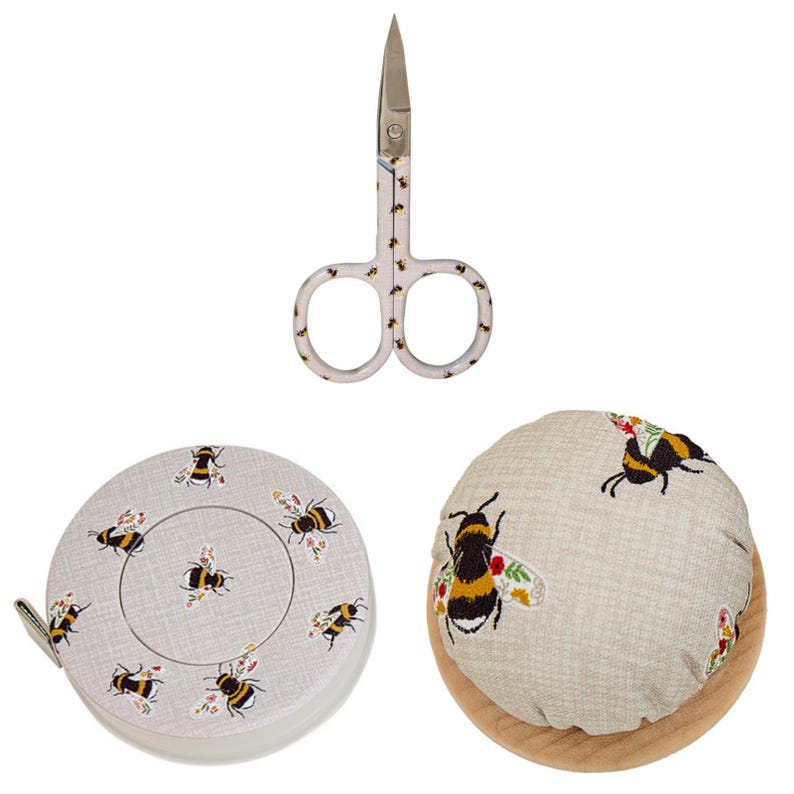 Puede incluir: Un conjunto de herramientas de costura con tem&aacute;tica de abejas. Incluye unas tijeras peque&ntilde;as, una cinta m&eacute;trica redonda y un alfiletero. Los art&iacute;culos est&aacute;n decorados con abejas bordadas y detalles florales, sobre un fondo neutro.