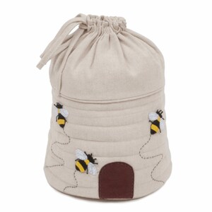 May include: A beige linen drawstring bag shaped like a beehive with a brown felt entrance and three embroidered bees.