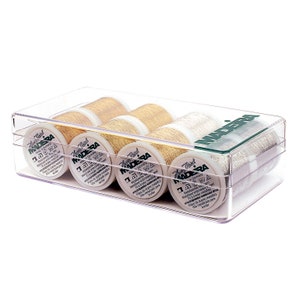 May include: A clear plastic box containing six spools of metallic thread. The spools are labeled "Made in Germany" and "Madera". The thread is available in gold and silver.