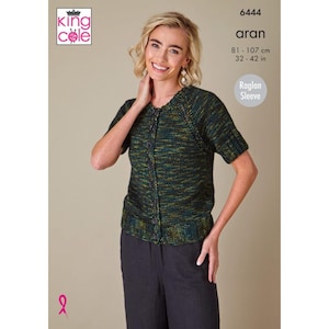 Può includere: Una donna indossa un cardigan a maniche corte, abbottonato, nei toni del verde, giallo e nero. Il cardigan ha uno scollo tondo e maniche raglan. Il testo "aran" e le misure di 81-107 cm sono inclusi.
