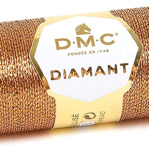 May include: A spool of gold metallic thread with the DMC Diamant brand label. The label features a horse logo and the text "DMC Fond&eacute;e en 1746 Diamant".
