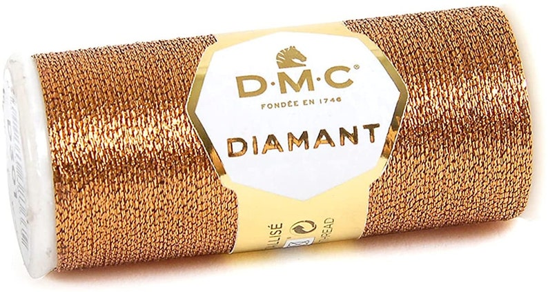 May include: A spool of gold metallic thread with the DMC Diamant brand label. The label features a horse logo and the text "DMC Fond&eacute;e en 1746 Diamant".
