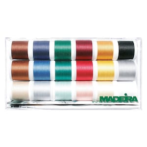 Pode incluir: Uma caixa de plástico transparente contendo 12 carretéis de fio Madeira. Os carretéis estão dispostos em duas filas de seis. As cores do fio são marrom, azul, verde, vermelho, dourado, preto, bege, prata, verde claro, rosa e branco.