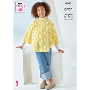 May include: A pale yellow cable-knit poncho with a ribbed neckline, worn over a long-sleeved white shirt and blue jeans. The image includes the King Cole logo, pattern number 6560, the text aran, and sizing for 1-8 years, 51-71 cm, 20-28 in.