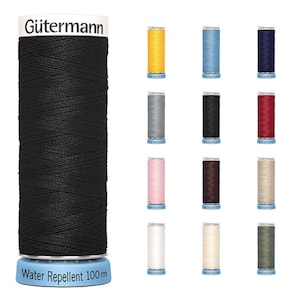 Könnte beinhalten: Eine Auswahl an Gütermann-Garnrollen in verschiedenen Farben, darunter Schwarz, Gelb, Blau, Marine, Grau, Rot, Rosa, Braun, Beige, Weiß und Grün. Die Hauptspule ist schwarz, mit "Water Repellent 100 m" auf der Basis.