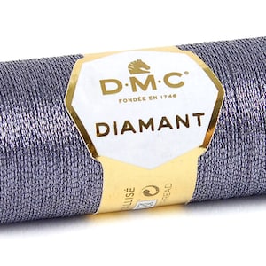 May include: A spool of DMC Diamant metallic thread in a silver-grey color. The spool is labeled with the DMC logo and the text "Diamant".