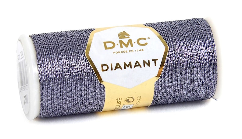 May include: A spool of DMC Diamant metallic thread in a silver-grey color. The spool is labeled with the DMC logo and the text "Diamant".