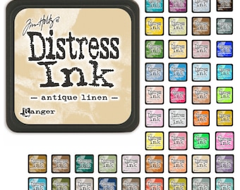 May include: A collection of Distress Ink pads in various colors, including Antique Linen,  a light beige color. The ink pads are arranged in a grid pattern and are labeled with the brand name "Distress Ink" and the color name.