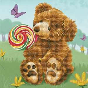 May include: A brown teddy bear with a colorful lollipop in its mouth. The bear is sitting on a green grassy field with yellow flowers.