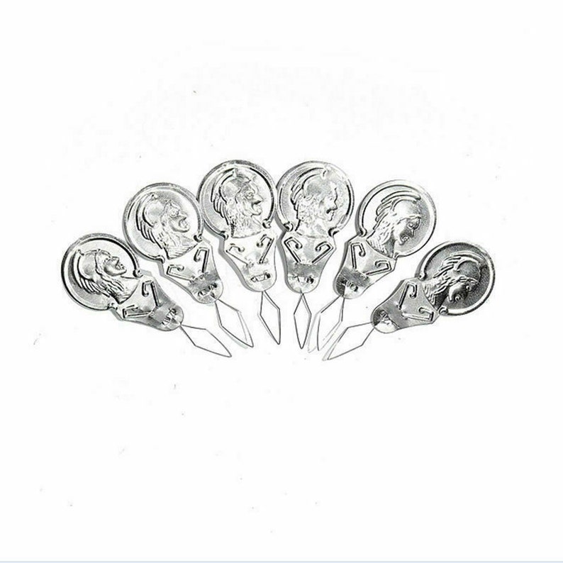 May include: Set of seven silver needle threaders with a decorative design. Each threader has a small loop at the end of the needle.
