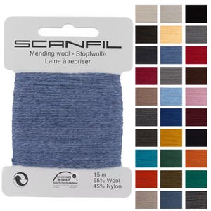 May include: A blue spool of "SCANFIL" mending wool. The label reads "Mending wool - Stopfwolle Laine à repriser." The spool contains 15 m of 55% wool and 45% nylon. A colour chart with various shades is displayed to the right.