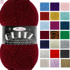 May include: A ball of deep red yarn with metallic flecks, wrapped in a black label that reads King Cole Glitz double knitting. To the right, a grid displays twenty-one additional yarn color variations, including blue, purple, pink, green, and gray.