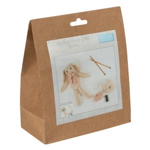 May include: A brown paper bag containing a knitting kit. The kit includes a knitted bunny, yarn, knitting needles, and instructions. The kit is labelled "My First Knitting Kit Bunny."