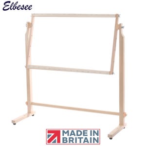 Pode incluir: Um suporte de bordado de madeira clara com uma moldura retangular ajustável. O suporte tem uma base sólida. O texto "Elbesee" está no topo. As palavras "MADE IN BRITAIN" também são visíveis.