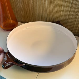 Puede incluir: Una taza de cerámica blanca con un asa negra y el texto "But First, Coffee" en negro y negrita. La taza está sobre una superficie blanca. La taza mide aproximadamente 10 cm de alto.