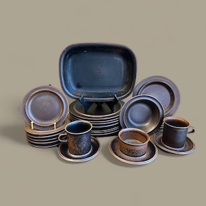 May include: A set of brown stoneware dinnerware with a speckled glaze. The set includes a large rectangular serving dish, plates, bowls, and cups.