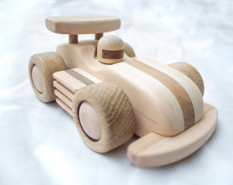 Puede incluir: Un coche de carreras de juguete de madera con un cuerpo a rayas blancas y marrones y un casco de piloto de madera. El coche tiene cuatro ruedas y un alerón en la parte trasera.