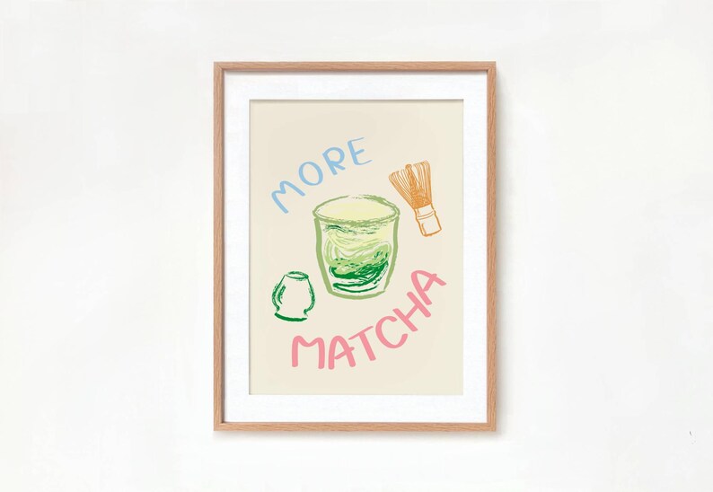 May include: A framed print with a light beige background featuring a green matcha drink in a glass with a green tea whisk and the words "More Matcha" in pink and blue.
