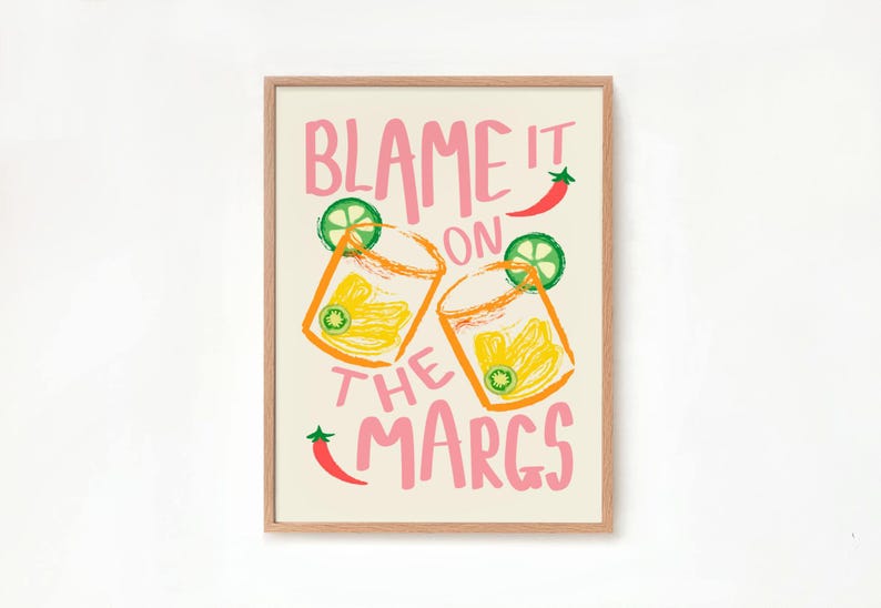 May include: A framed print with the text "Blame it on the Margs" in pink lettering. The print features two illustrations of margarita glasses with lime wedges and a red chili pepper.