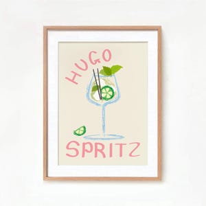 Op de afbeelding: Een ingelijste print met een lichtbeige achtergrond met een handgetekend ontwerp van een cocktailglas met een limoenpartje en een munttakje. De tekst "HUGO SPRITZ" is geschreven in roze letters.
