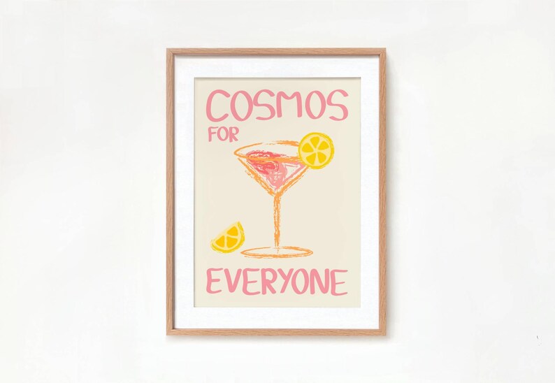 May include: A framed print with a pink and yellow illustration of a cocktail glass with a lemon wedge. The text "Cosmos for Everyone" is written in pink.