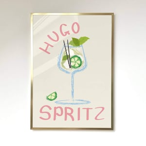 Op de afbeelding: Een gouden ingelijste print met een licht beige achtergrond. De print toont een handgetekende illustratie van een glas Hugo Spritz met een limoenpartje, muntblaadjes en twee zwarte rietjes. De woorden "Hugo Spritz" zijn in roze letters geschreven.