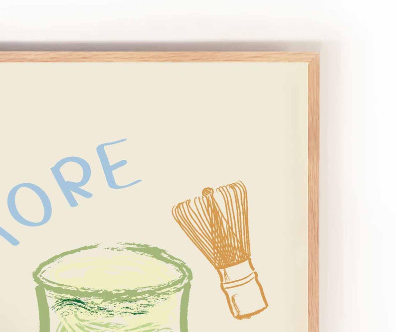 May include: A framed illustration of a glass of matcha with a whisk, with the word "MORE" written in blue letters on a cream background.
