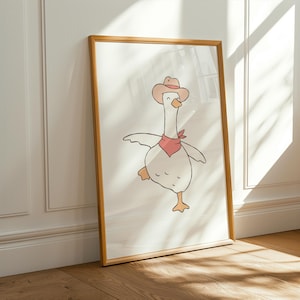 Könnte beinhalten: Gerahmter Kunstdruck mit einer Cartoon-Gans, die einen Cowboyhut und ein rotes Halstuch trägt. Die Gans ist mit einem erhobenen Bein dargestellt, als würde sie tanzen. Das Kunstwerk hat einen minimalistischen Stil mit einer hellen Farbpalette.