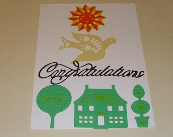 May include: A white card with a green house, two green trees, a yellow bird, a red and yellow sun, and the word "Congratulations" in black script.
