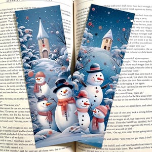 May include: Two rectangular bookmarks featuring a winter scene with snow-covered trees, a tall church steeple, and a small house. The illustrations depict multiple snowmen wearing colorful hats and scarves against a dark blue snowy background.