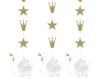 May include: Three white swan party decorations with gold crowns and stars hanging from strings. The swans have pink beaks and gold crowns. The stars and crowns are gold.