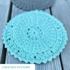 Può includere: Un sottobicchiere all'uncinetto di colore azzurro chiaro con un design circolare. Il sottobicchiere è realizzato con un punto a trama e ha un bordo smerlato.