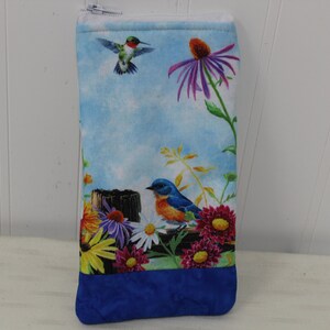 May include: A blue zippered pouch with a floral print featuring a hummingbird, a bluebird, and various flowers. The pouch has a blue fabric lining.